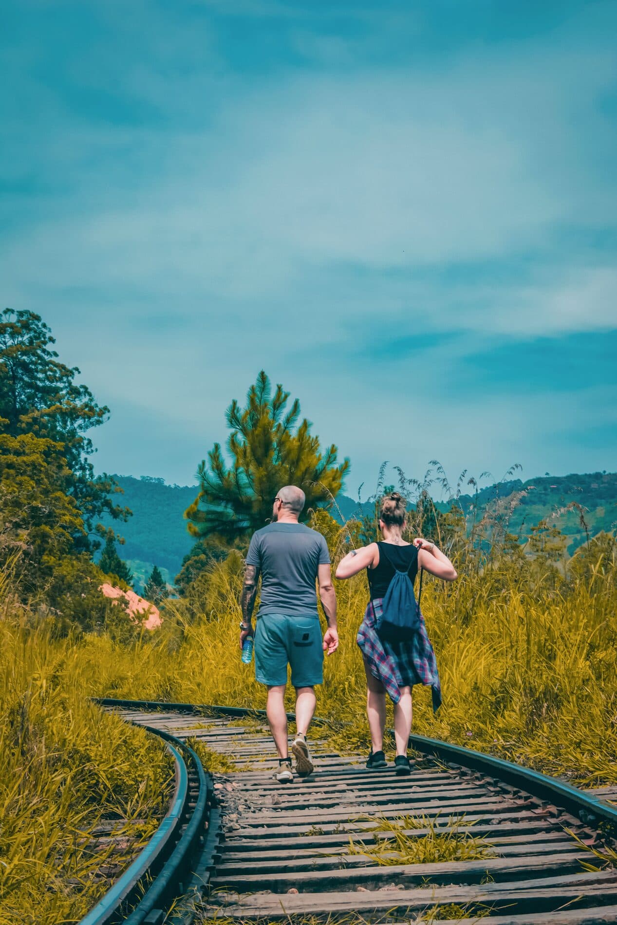 Travellers walking along a hill-country railway track